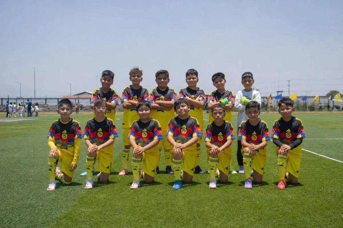 Foto de equipo de Nido Águila con uniforme amarillo, jugadores de pie y hincados alineados en la cancha