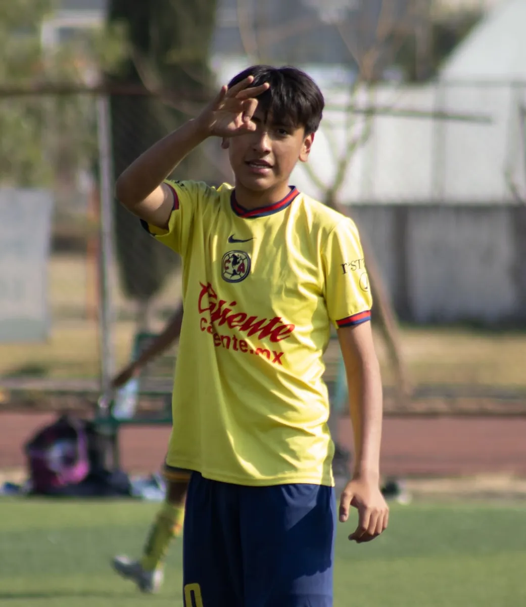 Jugador de Nido Águila con uniforme amarillo protegiéndose del sol con la mano durante el partido