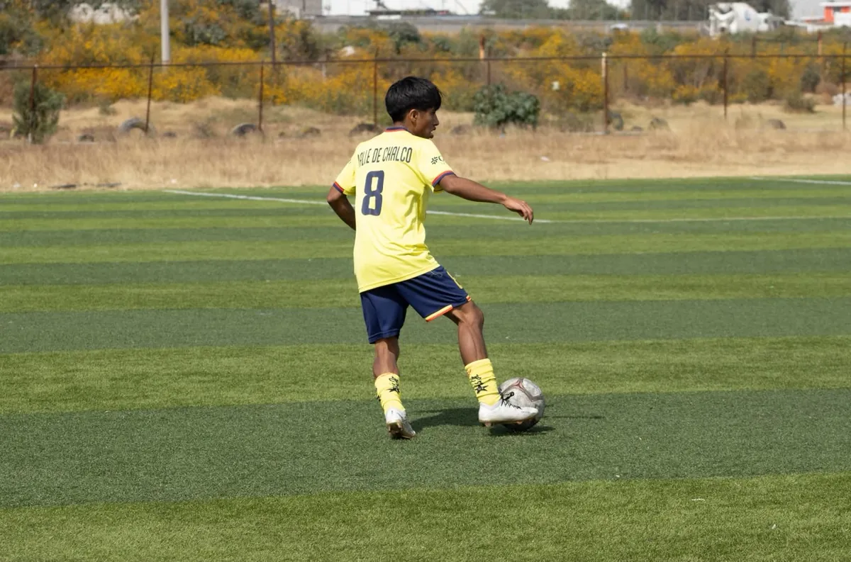 Jugador de Nido Águila con camiseta amarilla número 8 a punto de pasar el balón en la cancha